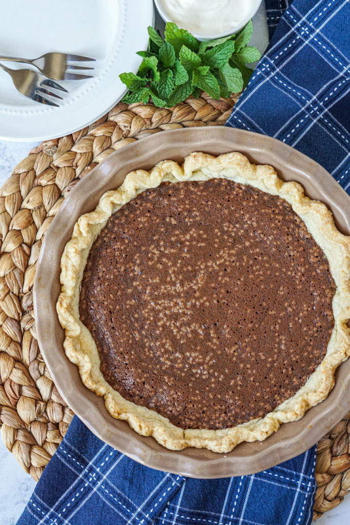 Aerial view of Chocolate Fudge Pie in a tan pie dish over a blue towel.