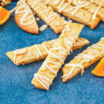 Three Orange Almond Cookie Bars on a blue surface with more in the background.