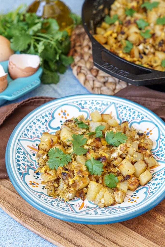Batata Wa Bayd (Lebanese Potatoes and Eggs) on a blue and white plate with cilantro.