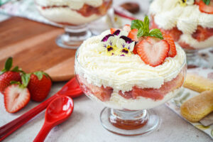 Tiramisu alle Fragole (Italian Strawberry Tiramisu) in three glasses with sliced strawberries, mint sprig, and pansies.