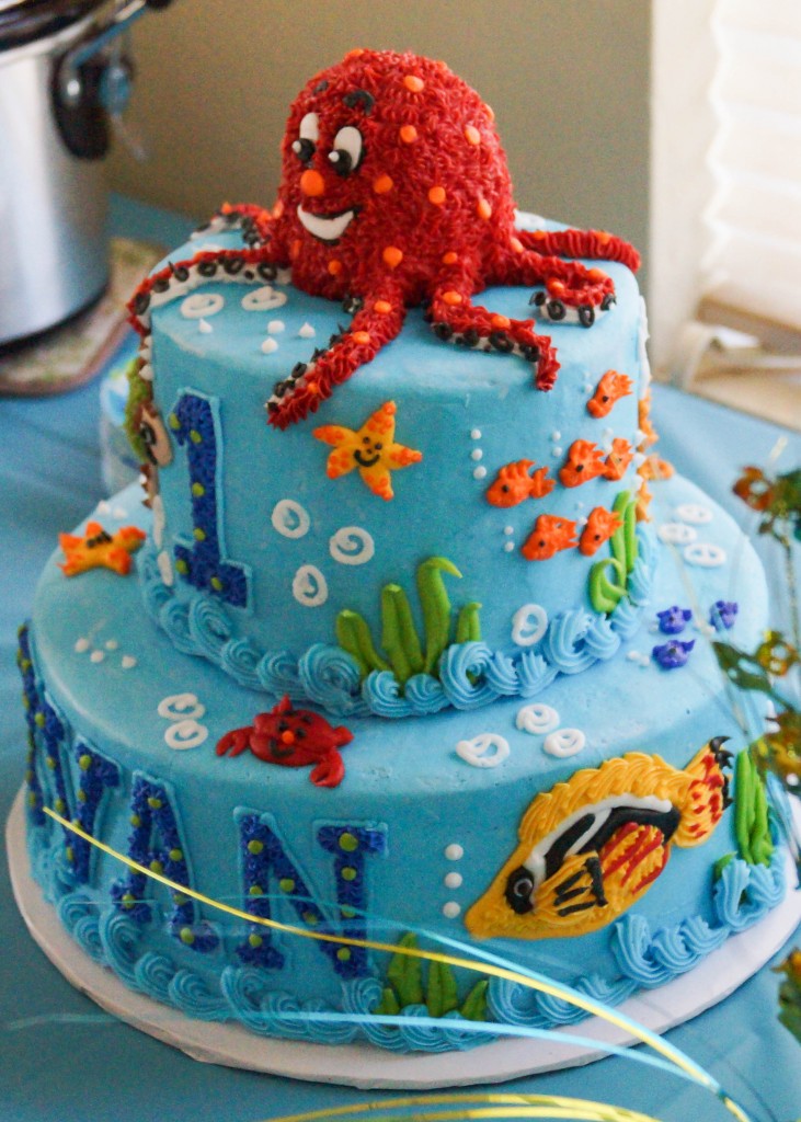 Side view of blue birthday cake with yellow fish, orange fish, and red octopus.