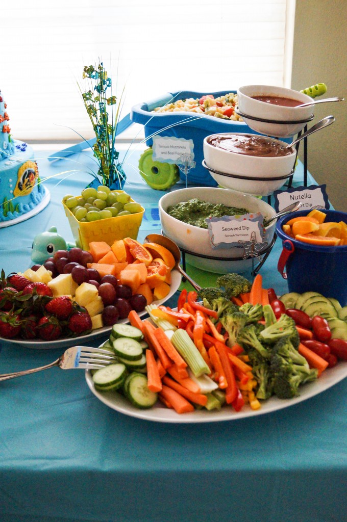 Vegetables, fruits, and dips on white platters.