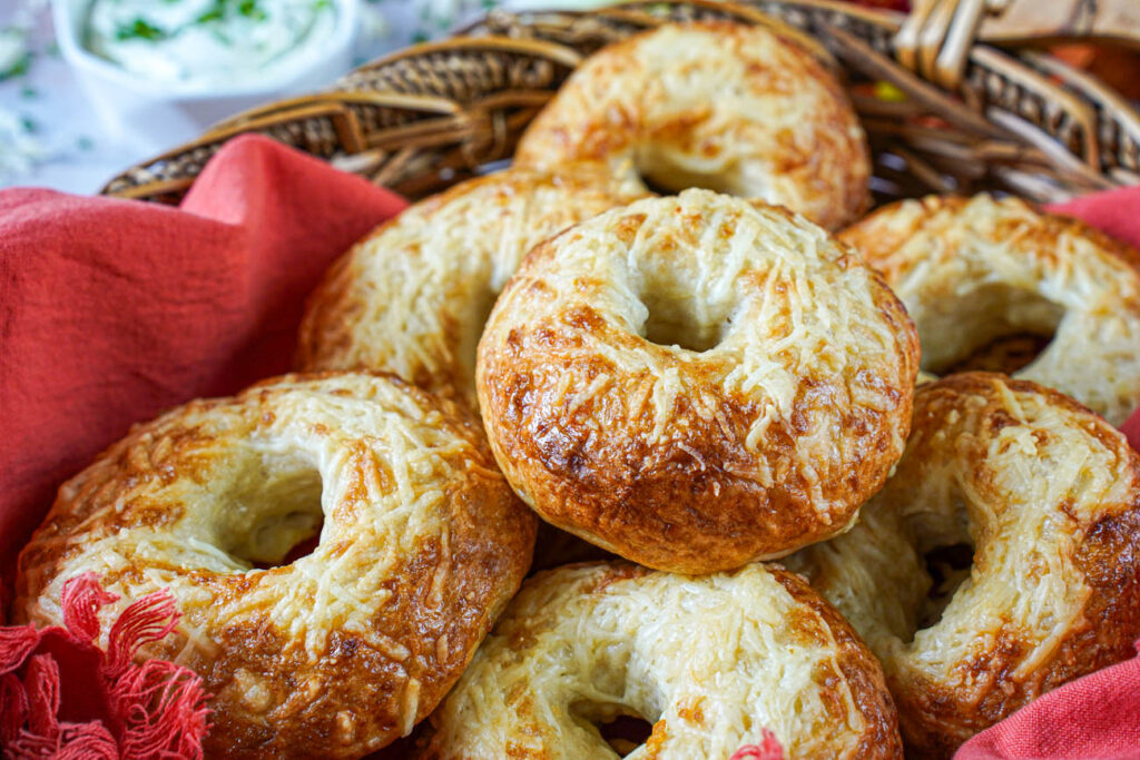 A pile of Asiago Bagels in a basket.