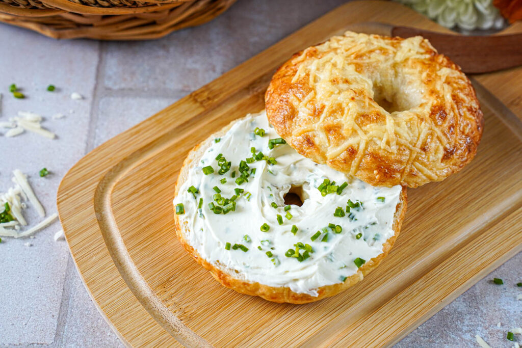 Asiago Bagel cut in half with chive cream cheese spread through the center.