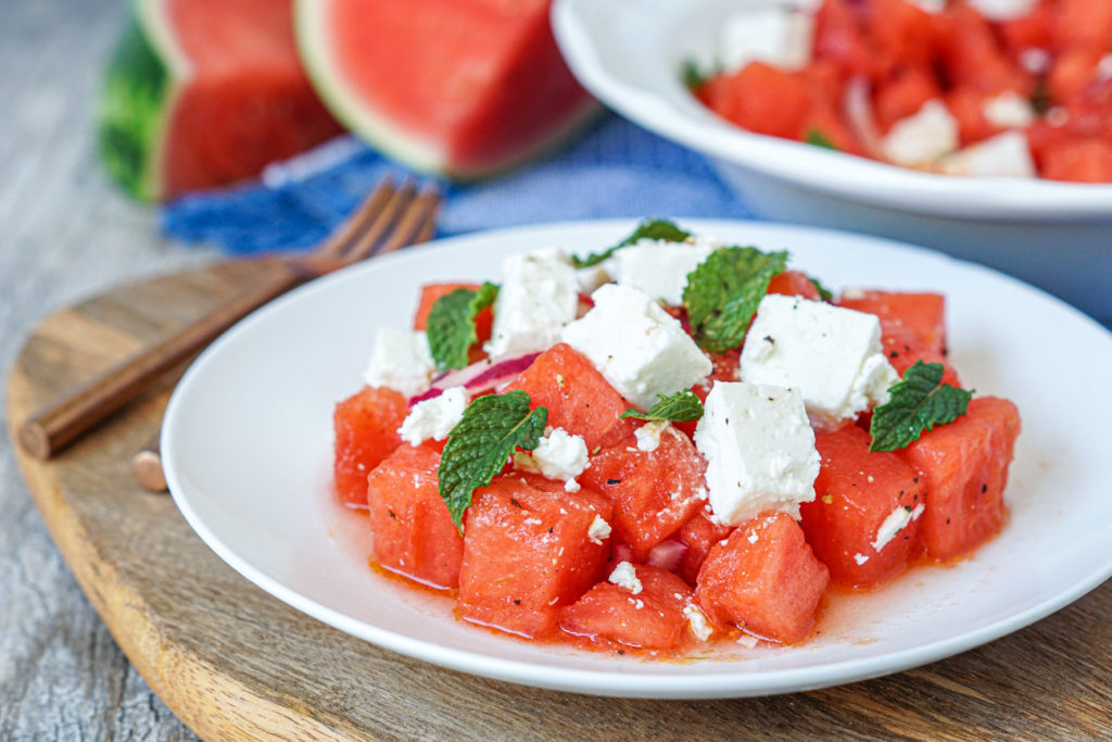 Karpouzi me Feta (Greek Watermelon with Feta) on a white plate over a wooden board.