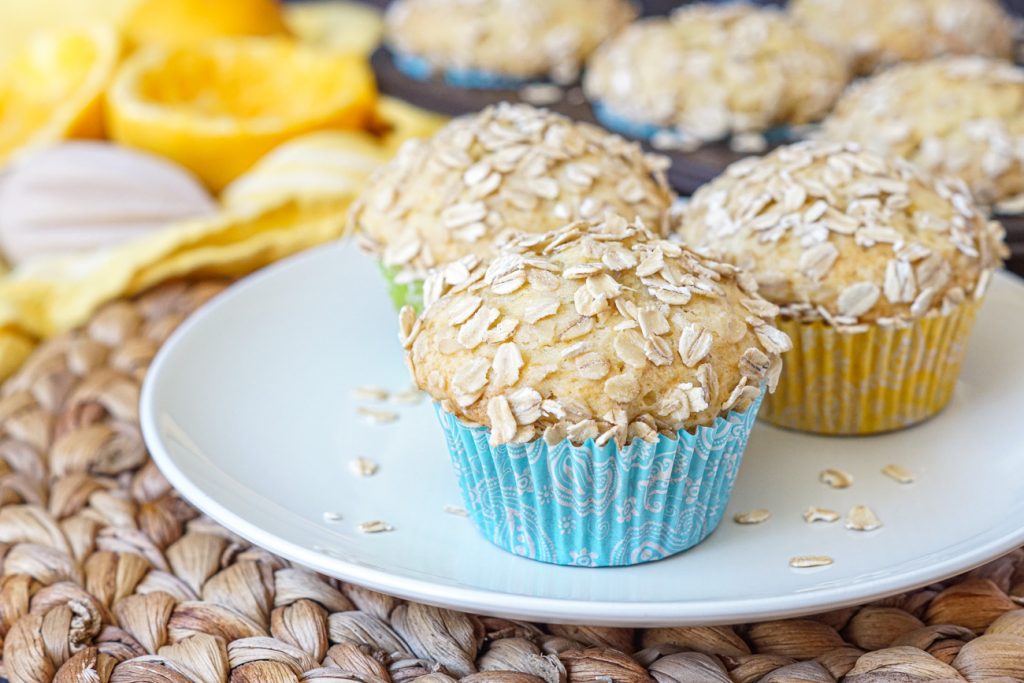 Orange Oat Muffins in blue and yellow wrappers on a white plate