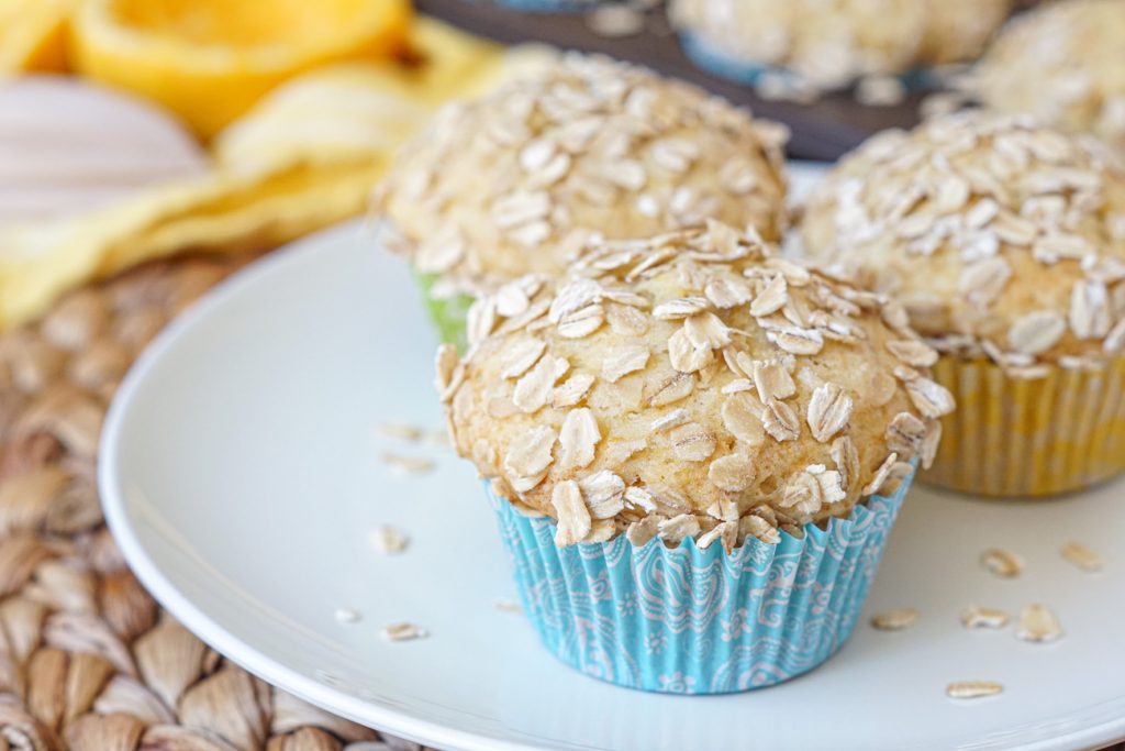 Close up of Orange Oat Muffins covered in oats on a white plate.