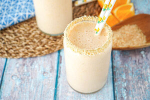 Pineapple Orange Coconut Smoothie in two glasses rimmed with toasted coconut flakes.