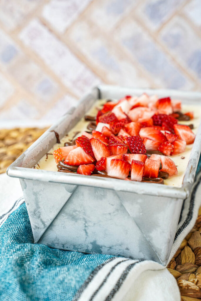 Strawberry Chocolate Hazelnut Ice Cream in a loaf pan with diced strawberries on top.