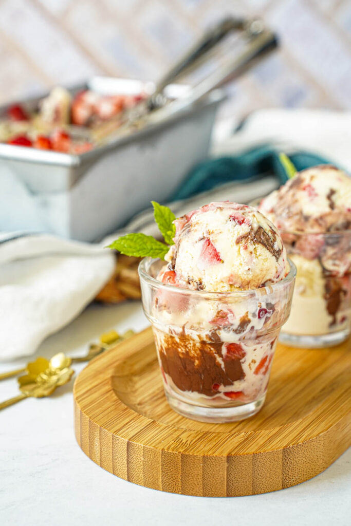Close up of Strawberry Chocolate Hazelnut Ice Cream in two cups with a loaf pan in the background.
