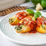 Three Kale and Ricotta Stuffed Shells on a plate with basil.