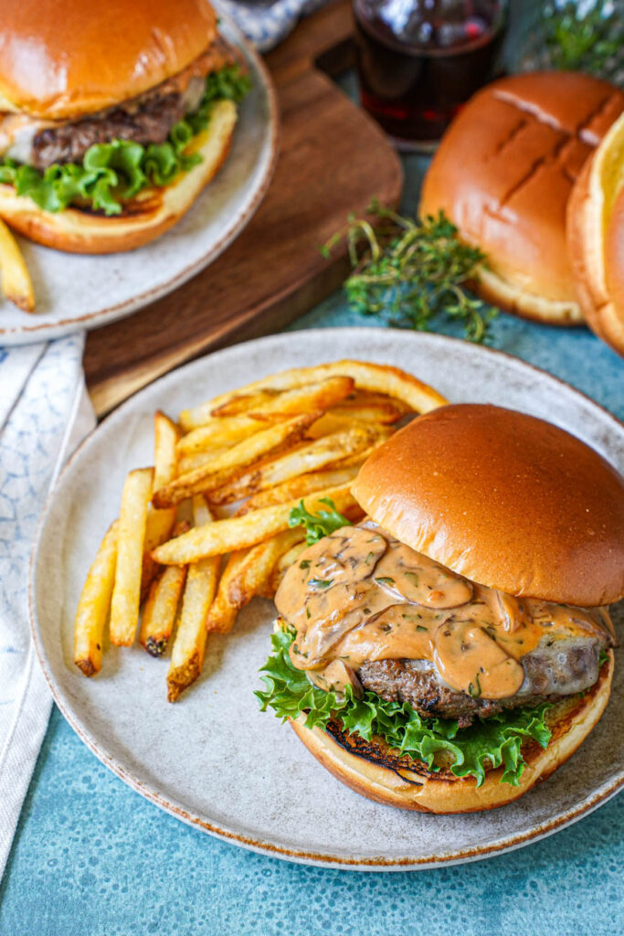 Close up of Marsala Burgers on two plates with fries.