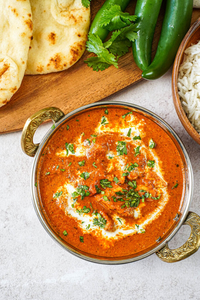 Aerial view of Murgh Makhani (Butter Chicken) in a bowl topped with cream and chopped cilantro.