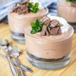 Nutella Mascarpone Cups in three glasses with whipped cream, mint, and chocolate flakes.