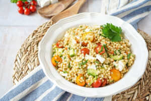 Pearl Couscous Salad in a large white bowl with fresh parsley.