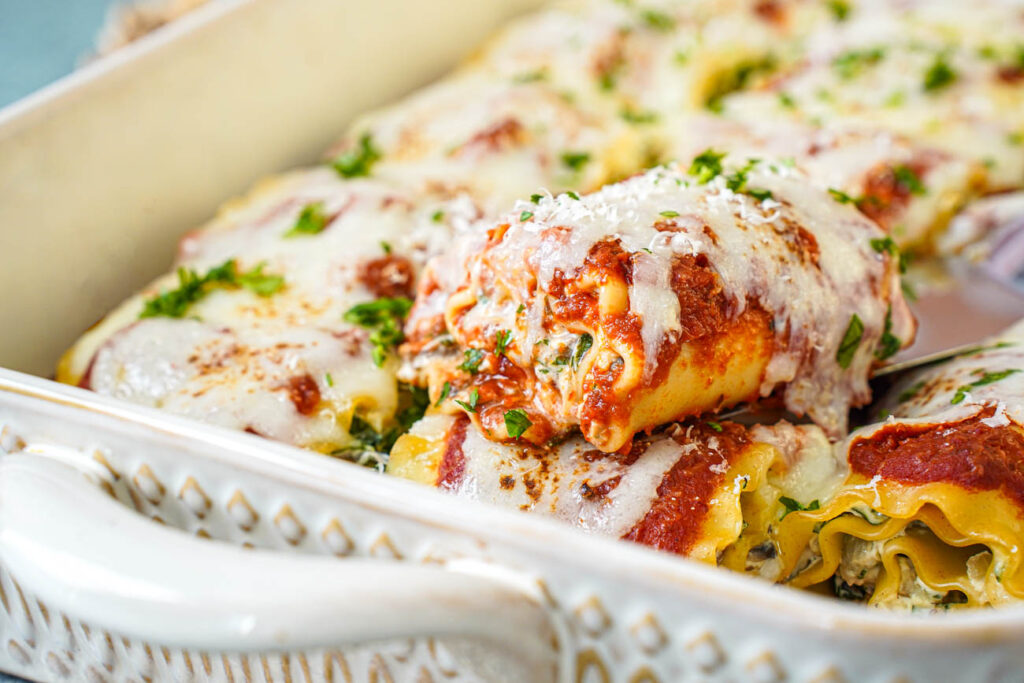 A spatula lifting a Mushroom Kale Lasagna Roll out of a pan.
