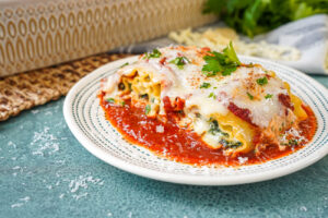 Two Mushroom Kale Lasagna Rolls on a plate with tomato sauce and fresh parsley.
