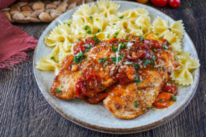 One-Pan Chicken with Cherry Tomatoes on a plate with farfalle pasta.
