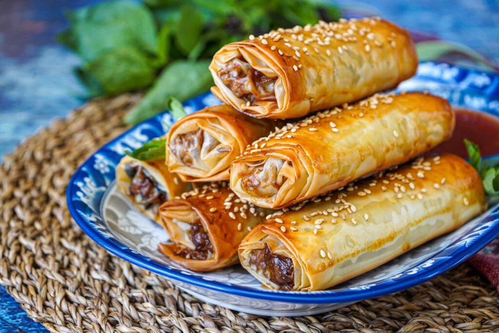 A stack of Thai Basil Chicken Phyllo Rolls on a blue and grey platter.