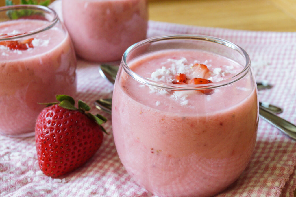 Strawberry Coconut Soup in a clear glass with diced strawberries and coconut flakes.