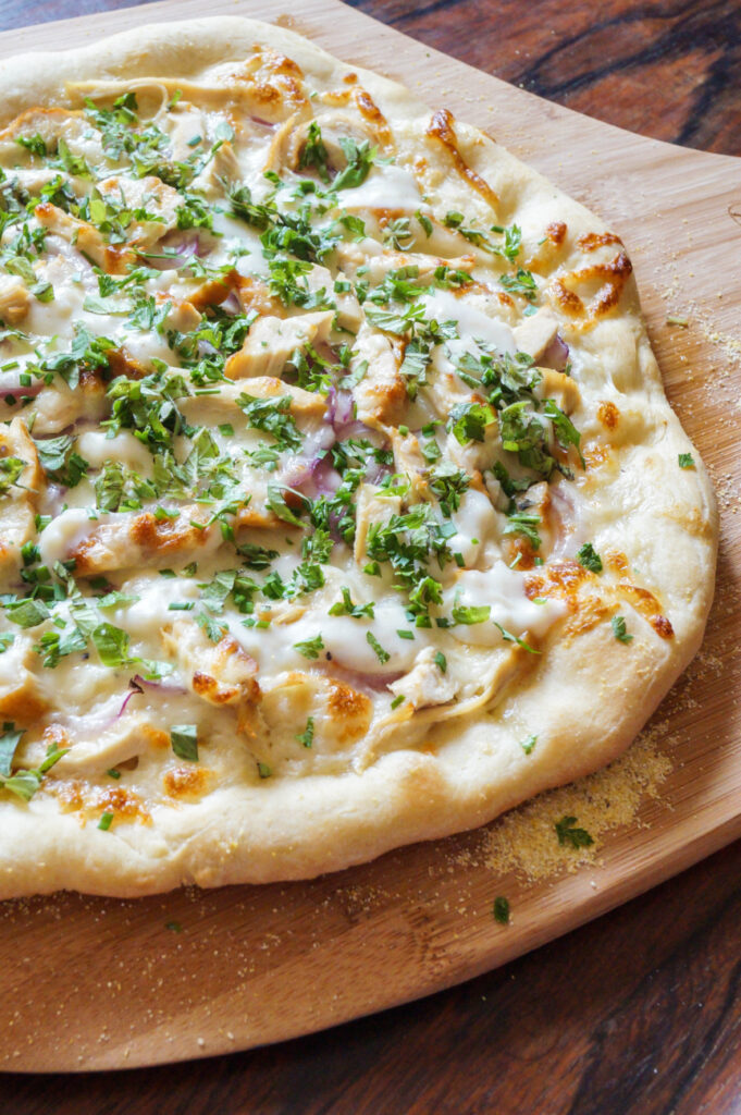 White Pizza with Chicken and Fresh Herbs on a wooden board.