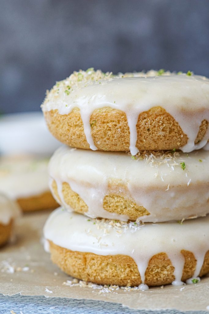 Side view of three stacked Coconut Lime Baked Donuts topped with a sweet lime glaze. 