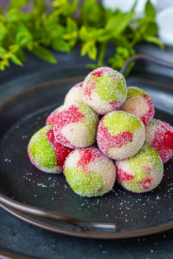 Stack of sugar coated Kaber Ellouz (Tunisian Almond Balls) with mint in the background.