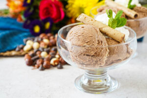 Gelato al Gianduia (Chocolate Hazelnut Gelato) in a glass bowl with whipped cream, mint, and pirouline cookie.