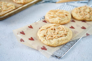 White Chocolate Cookies with Peanut Butter Drizzle on a parchment-lined wire rack.