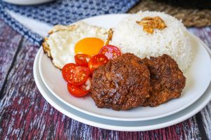 Longganisang Hubad (Filipino Garlic Sausage Patties) on a plate with rice, tomatoes, and egg.