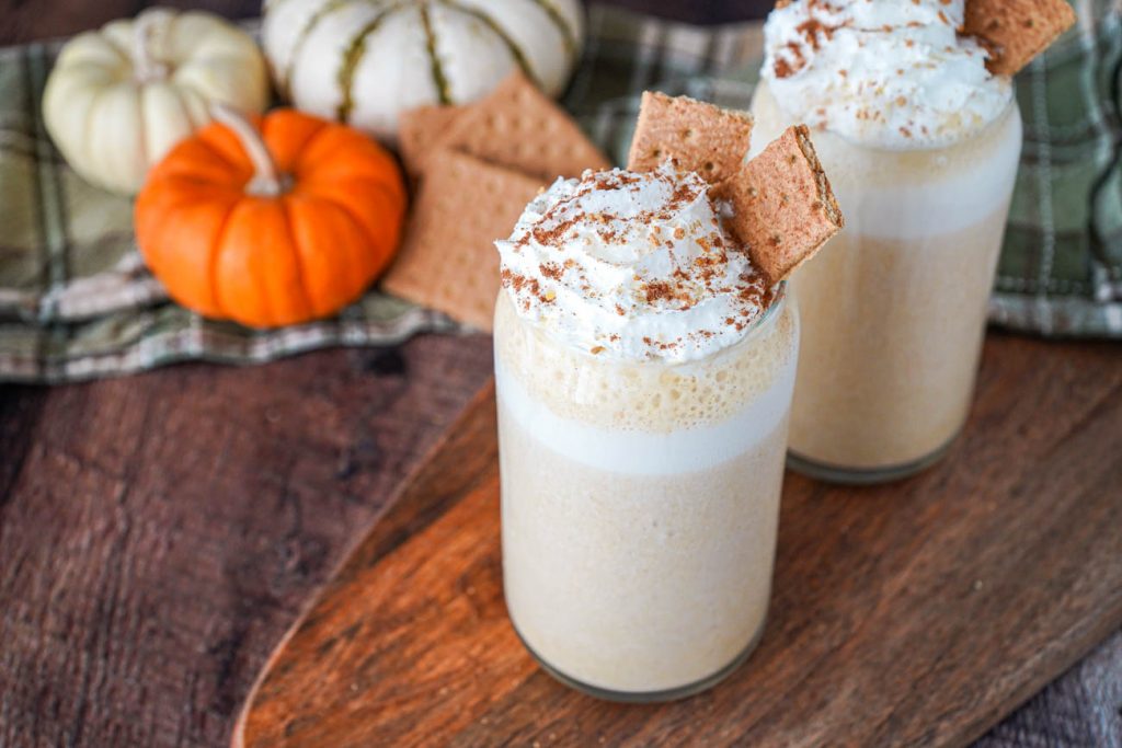 Pumpkin Cheesecake Smoothie in two glasses with whipped cream and graham crackers.