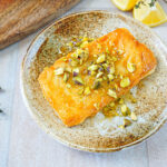 Saganaki (Greek Fried Cheese) on a plate with chopped pistachios and drizzled honey.