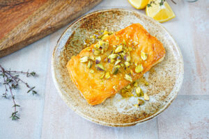 Saganaki (Greek Fried Cheese) on a plate with chopped pistachios and drizzled honey.
