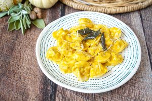 Tortellini with Pumpkin Cream Sauce on a white and green plate.