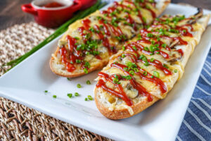 Zapiekanka (Polish Toasted Mushroom and Cheese Bread) on a white rectangular plate.