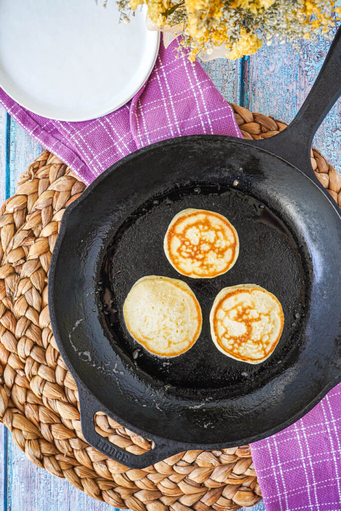 Aerial view of three Lemon Pikelets in a cast iron skillet.