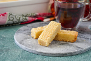 Three Scottish Shortbread on a marble board next to a cup of tea.