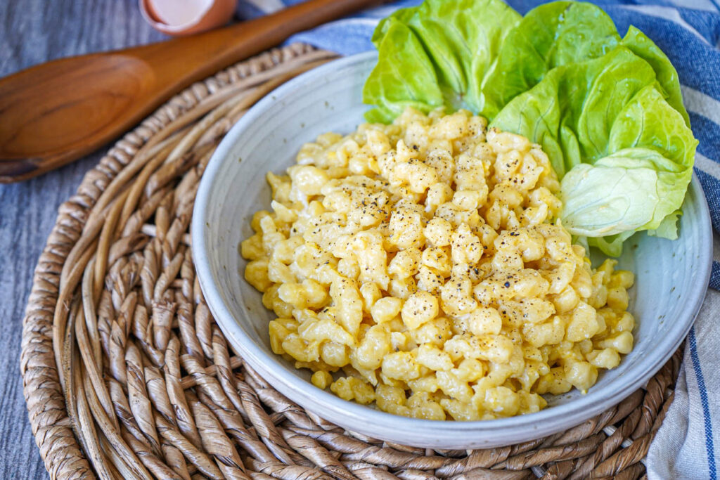Tojásos Nokedli (Hungarian Dumplings with Eggs) in a bowl with lettuce leaves.