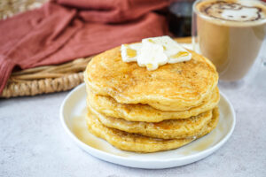Four Hottokeki (Japanese Hot Cakes) on a white plate next to coffee cup.