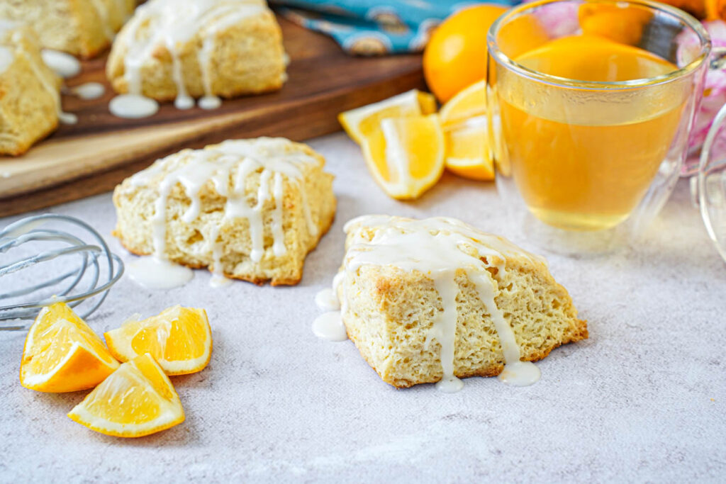Side view of Meyer Lemon Scones next to a glass of tea and Meyer lemon wedges.