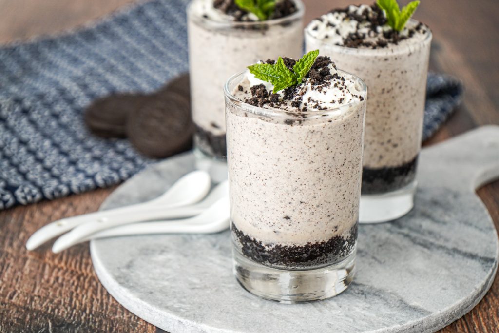 Cookies and Cream Mousse in three glasses with whipped cream and crushed cookies.