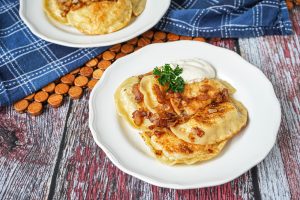 Pierogi Ruskie (Polish Dumplings with Potato and Cheese) on two white plates.