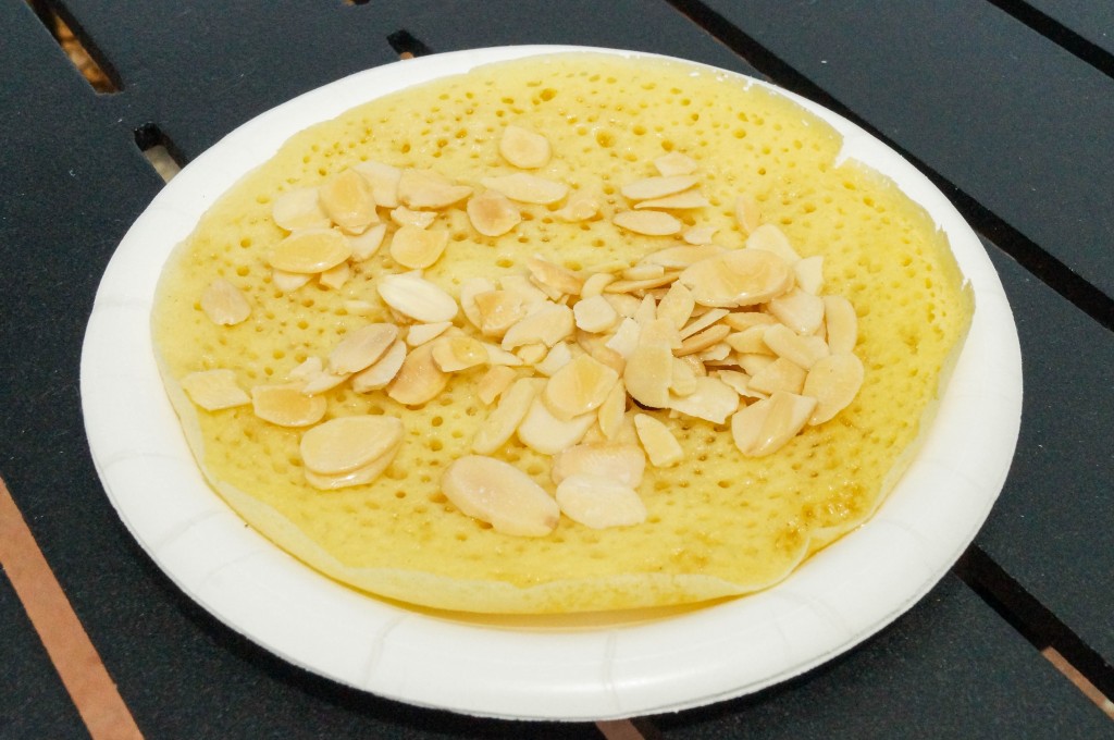 Baghrir (Moroccan Semolina Pancakes) on a white plate with sliced almonds.