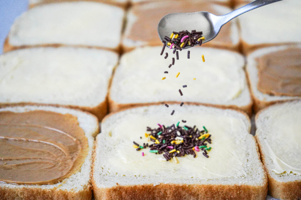 Adding sprinkles to a slice of buttered bread.