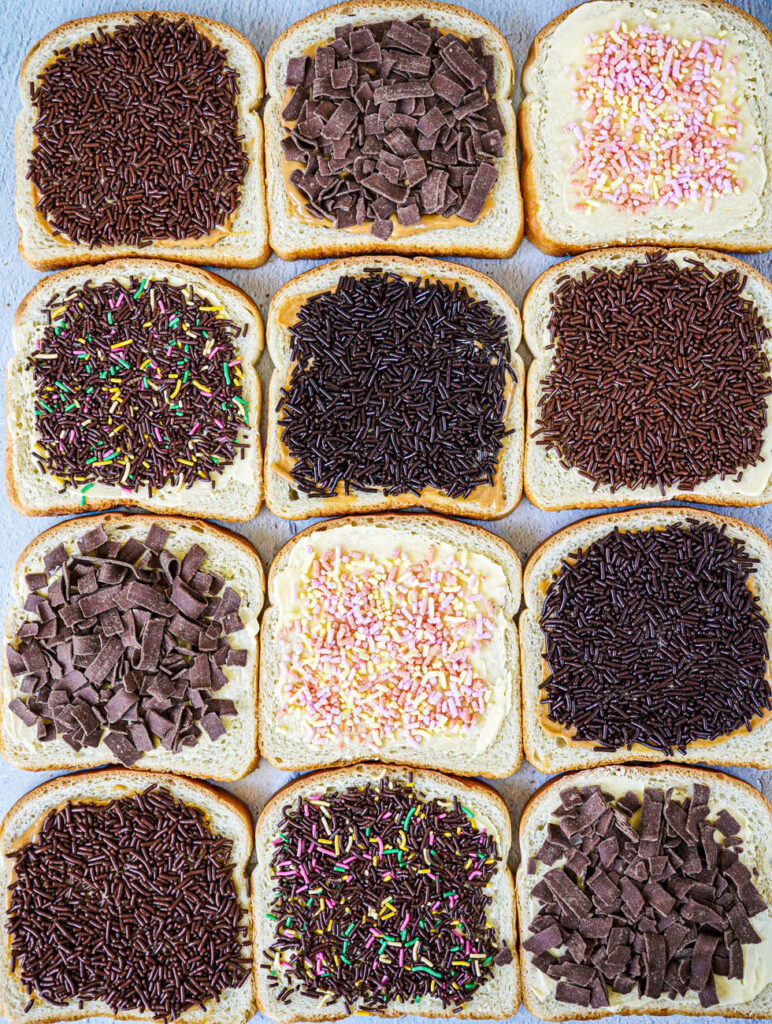 Aerial view of twelve slices of Broodje Hagelslag (Dutch Bread with Sprinkles) with different sprinkles.
