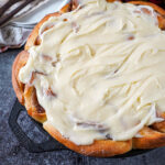 Cast Iron Cinnamon Rolls covered in a thick cream cheese frosting.