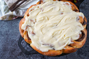 Cast Iron Cinnamon Rolls covered in a thick cream cheese frosting.