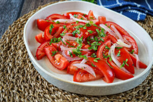 Ensalada Chilena (Chilean Tomato and Onion Salad) on a plate with a sprinkling of chopped cilantro.