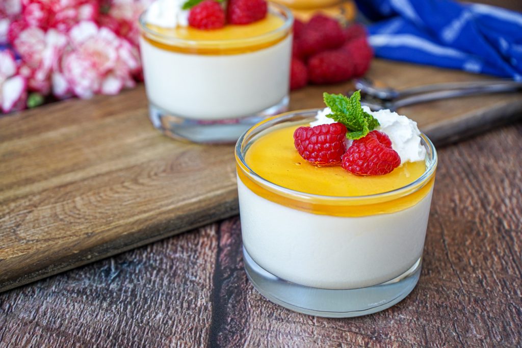 Honey White Chocolate Mousse in two glasses with fresh raspberries and whipped cream.