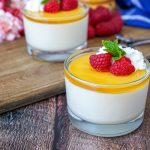 Honey White Chocolate Mousse in two glasses with whipped cream and raspberries.